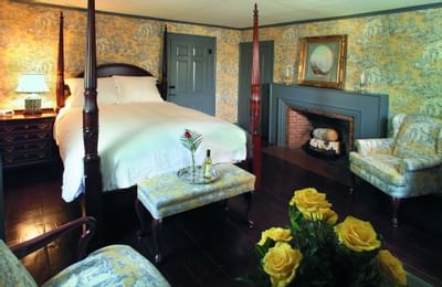 Blue patterned couch near wooden coffee table in front of canopy bed in Guest House at Farmington Inn and Suites