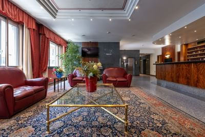 Lobby featuring elegant red leather furniture & decorative rug at Hotel Crivi's in Milan