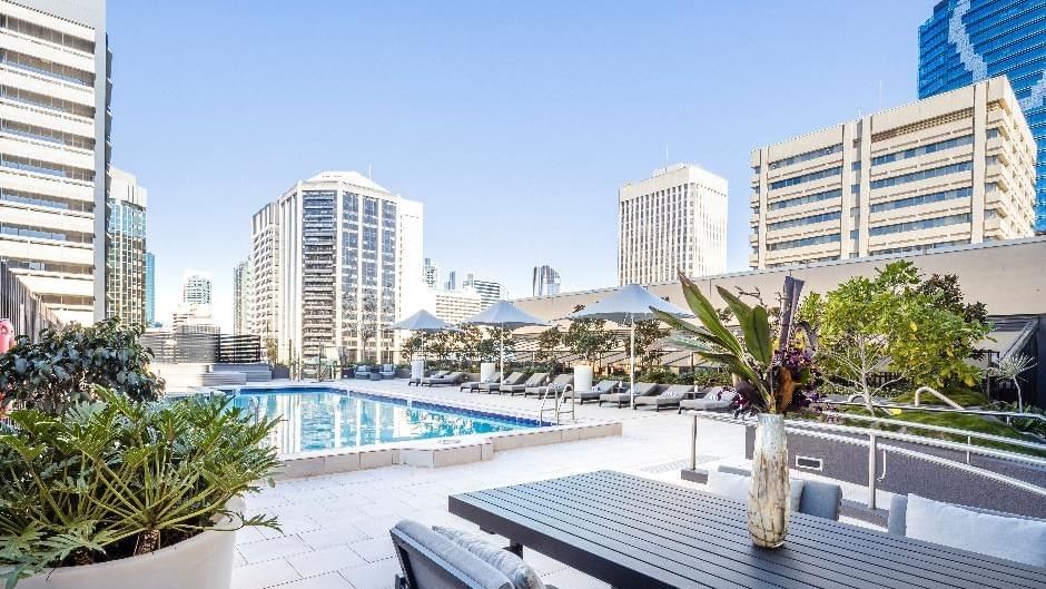 Rooftop Poolside Dining area with city skyline views, deck chairs and plants at Sofitel Brisbane Central