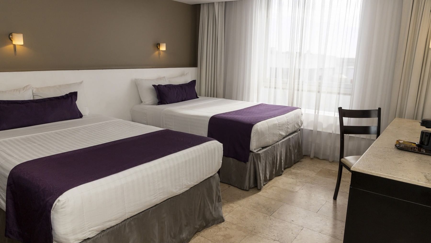 Two beds, wall lamps, work desk & chair in a room at Gamma Puebla Senorial