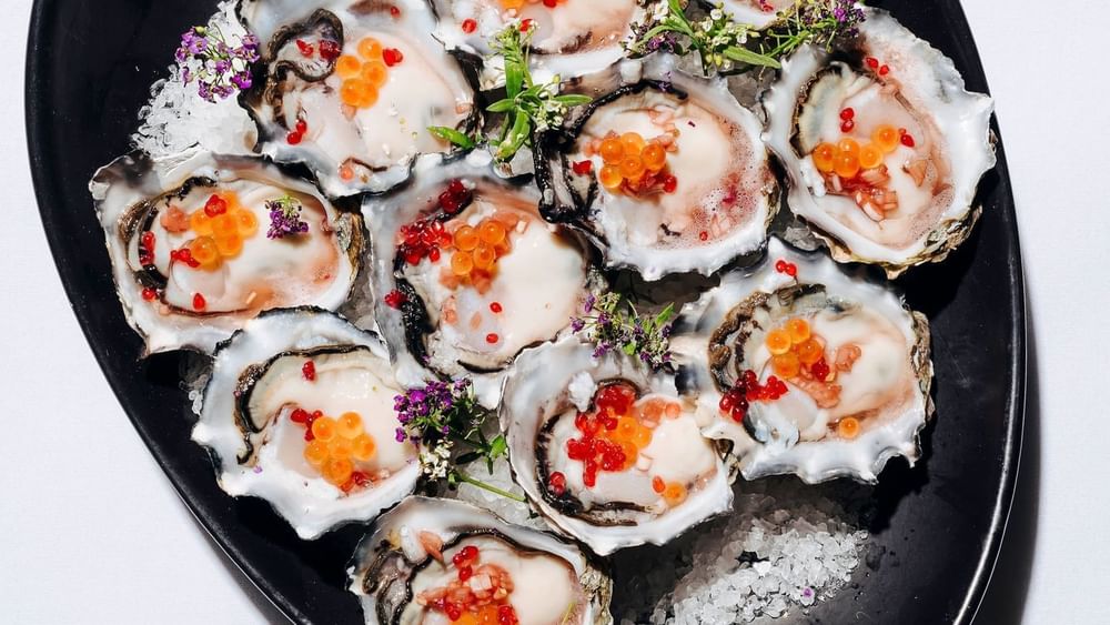 Platter of fresh oysters topped with orange roe and delicate herbs in Forest Room at Novotel Sydney Olympic Park