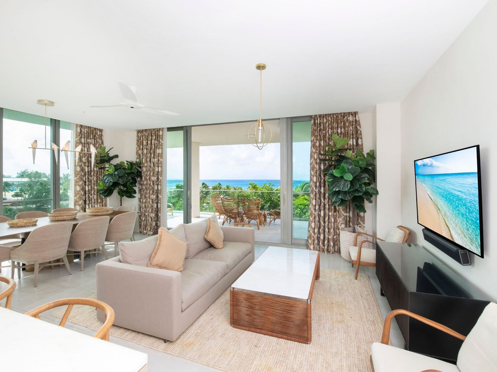 Living room with coastal views, featuring a sofa, dining area, and tropical decor in S202 Room at The Residences at Seafire.