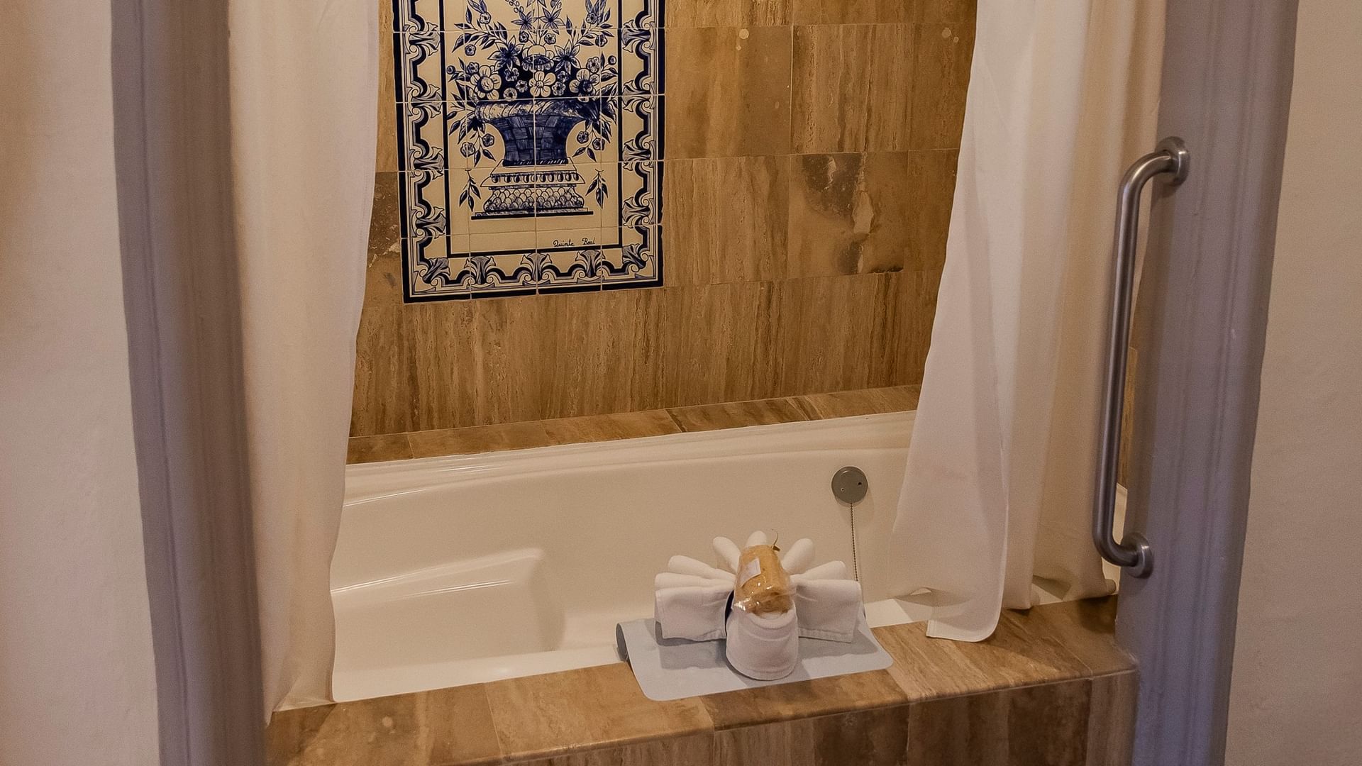King Master Suite bathroom with soaking tub, decorative tile artwork, and white towels at Quinta Real Zacatecas