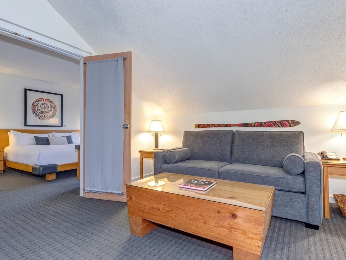 A hotel room with a bed, couch, coffee table, and two nightstands with lamps.