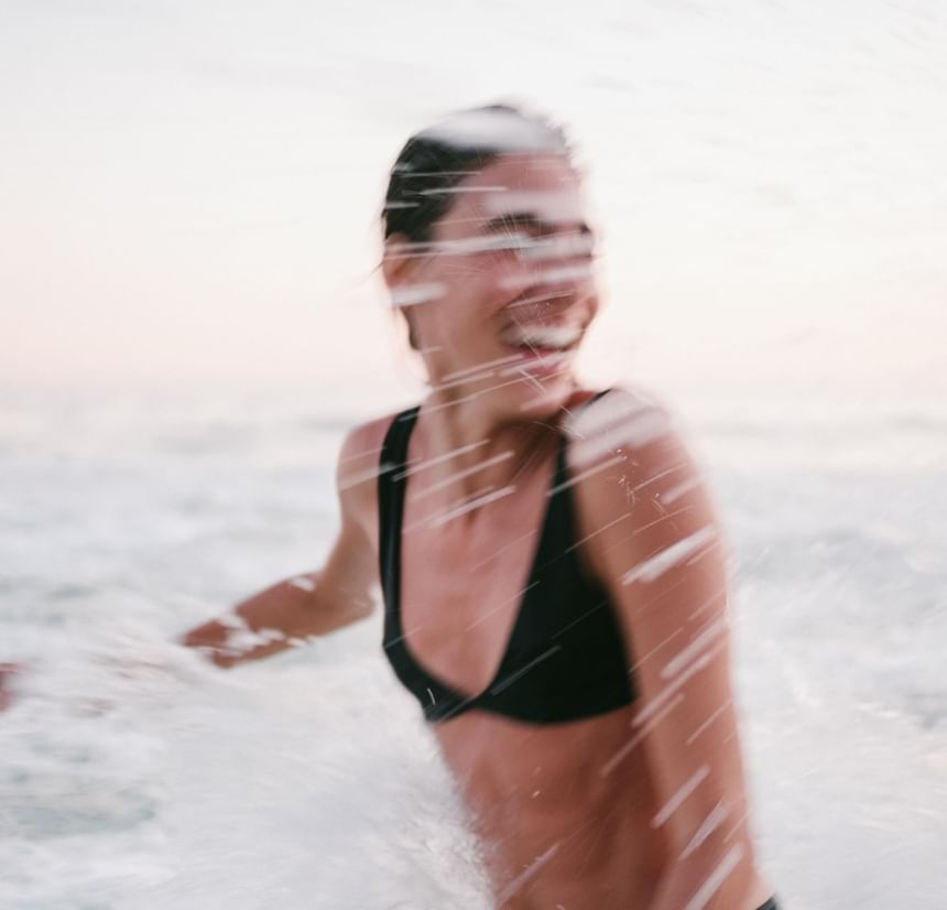 Mulher de bikini preto brincando com água na praia do leblon para fotos 