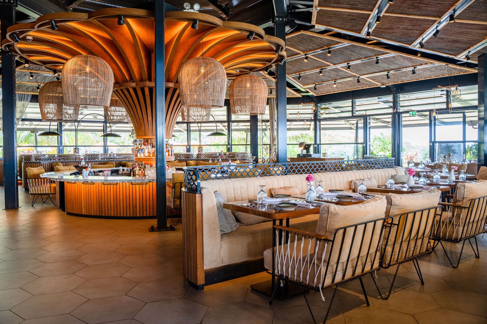 Interieur van Breeze Restaurant met een centrale bar, luxe zitplaatsen en warme verlichting bij Golden Rock Resort