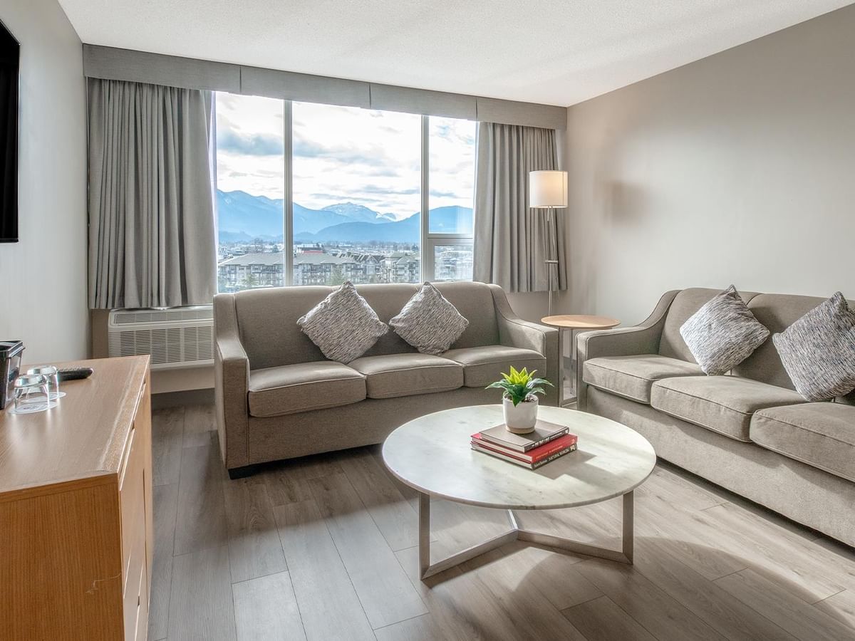 Living area with large windows, couches, and coffee table at Coast Chilliwack Hotel by APA.
