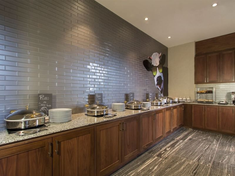 A buffet with silver trays and stacked plates at Fiesta Inn