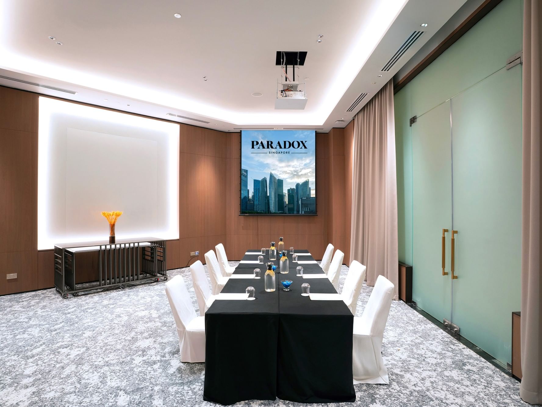 Boardroom setup in a meeting room at Paradox Singapore, with a long rectangular table surrounded by executive chairs, equipped for formal meetings and discussions in a professional environment.