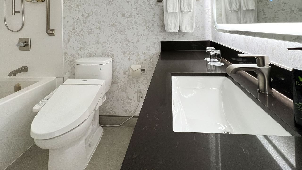 Hotel washroom with TOTO washlet, mirror, sink, soap, and bathtub.
