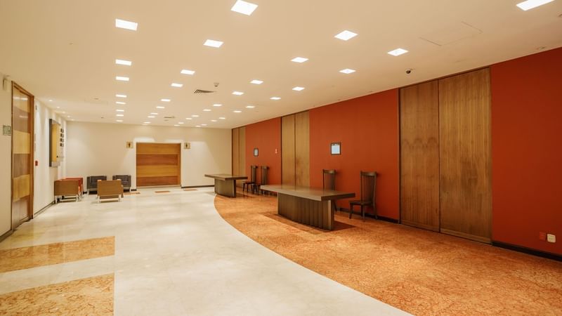 Modern hotel lobby featuring a long orange wall and sleek wooden tables at Camino Real Pedregal Mexico