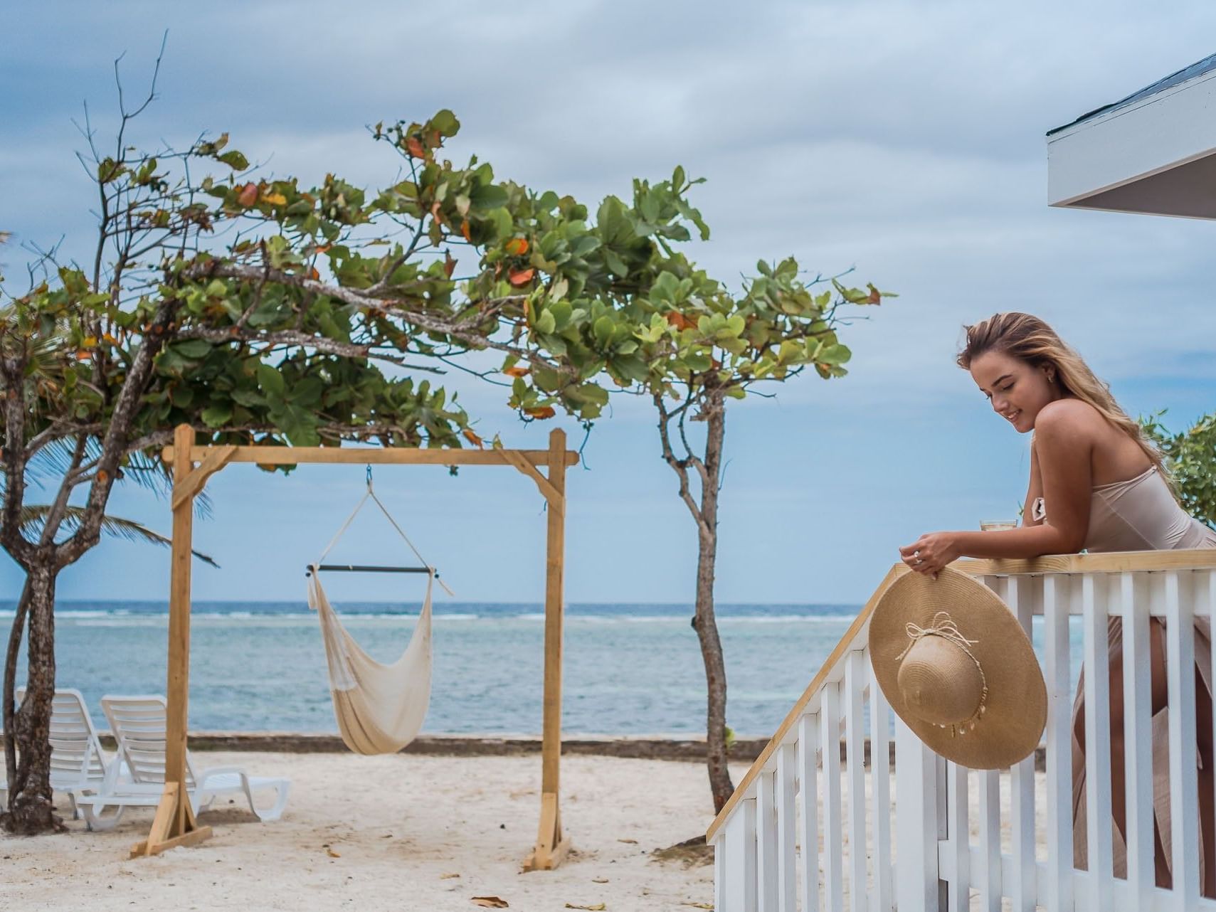 Guest on stairs overlooking a beach and a swing in One Bedroom Oceanfront Villa at Barefoot Cay Resort & Marina