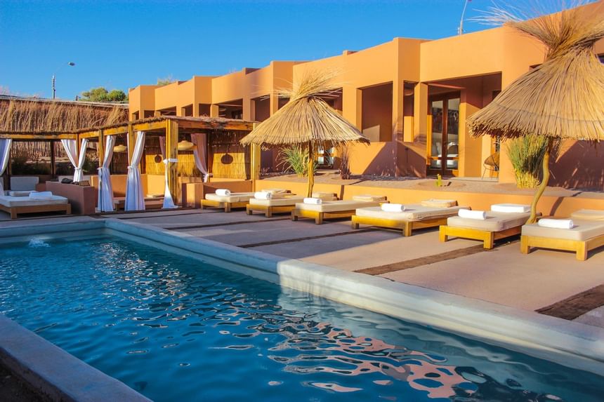 outdoor pool & chairs with umbrellas at NOI Casa Atacama Hotel