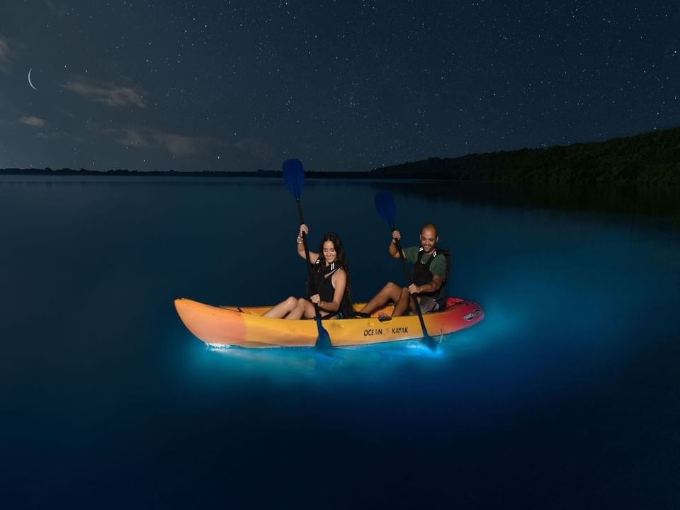 Landscape view of Couple kayaking in Laguna Grande at night near Las Casitas Village