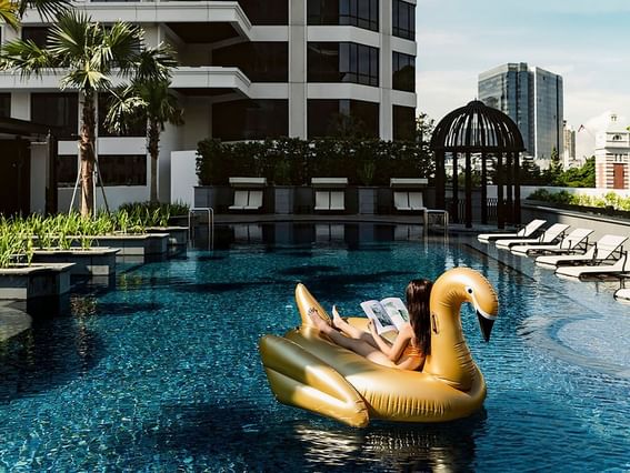 A girl reading a book on a floatie on a pool of Park Hotel Group