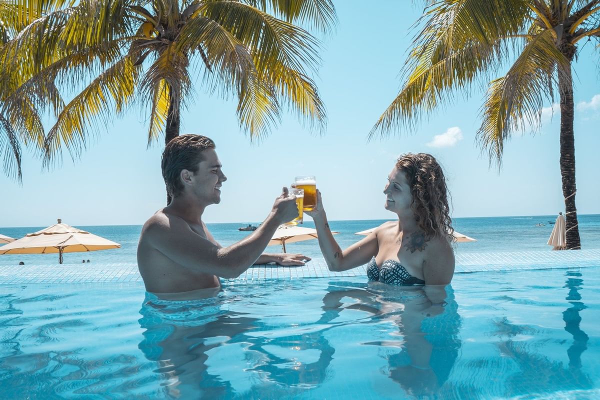 couple cheersing with drinks in pool