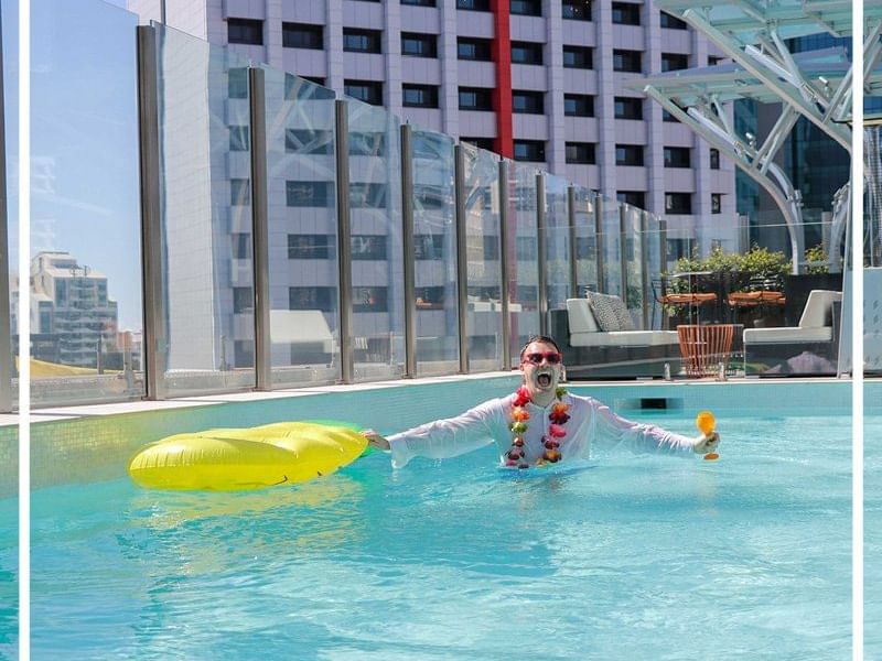 Man enjoying in the rooftop pool at Pullman & Mercure Brisbane King George Square