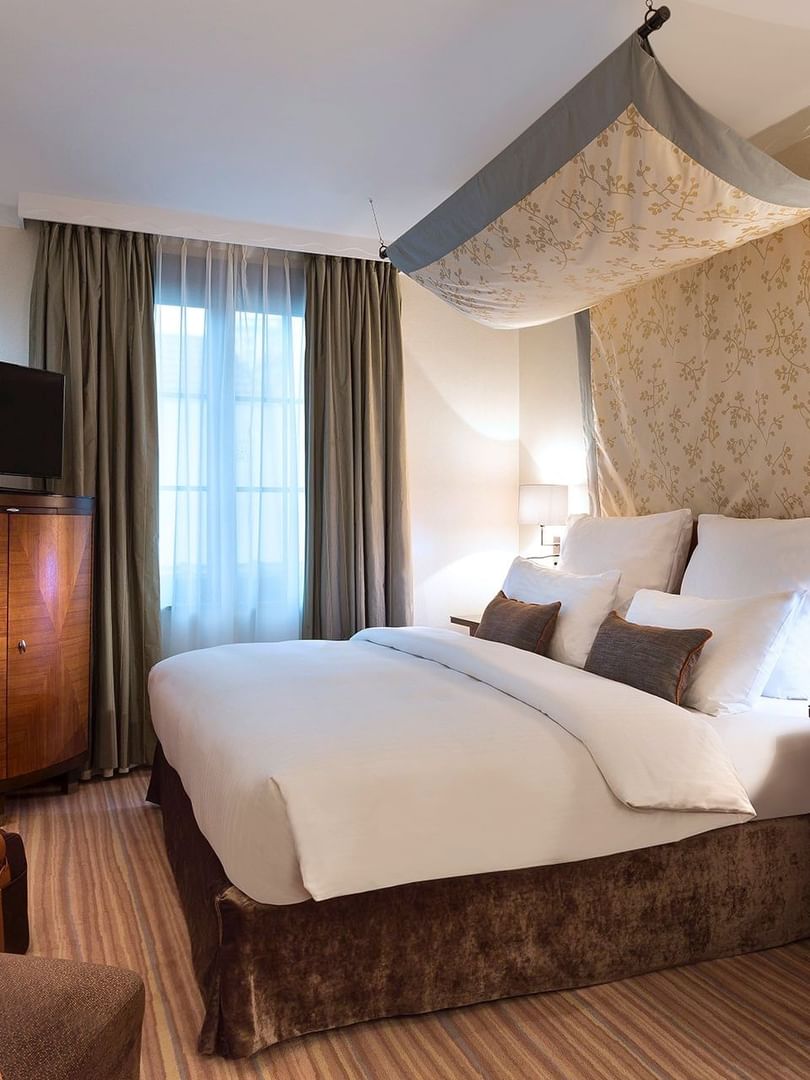 Lit et coin salon avec espace de travail dans une chambre Premium à l'hôtel Warwick Brussels