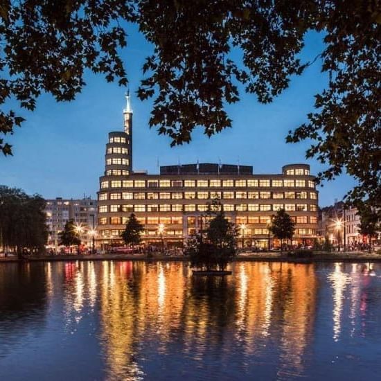 Night view of the Flagey building reflected in the water near Hotel Barsey by Warwick