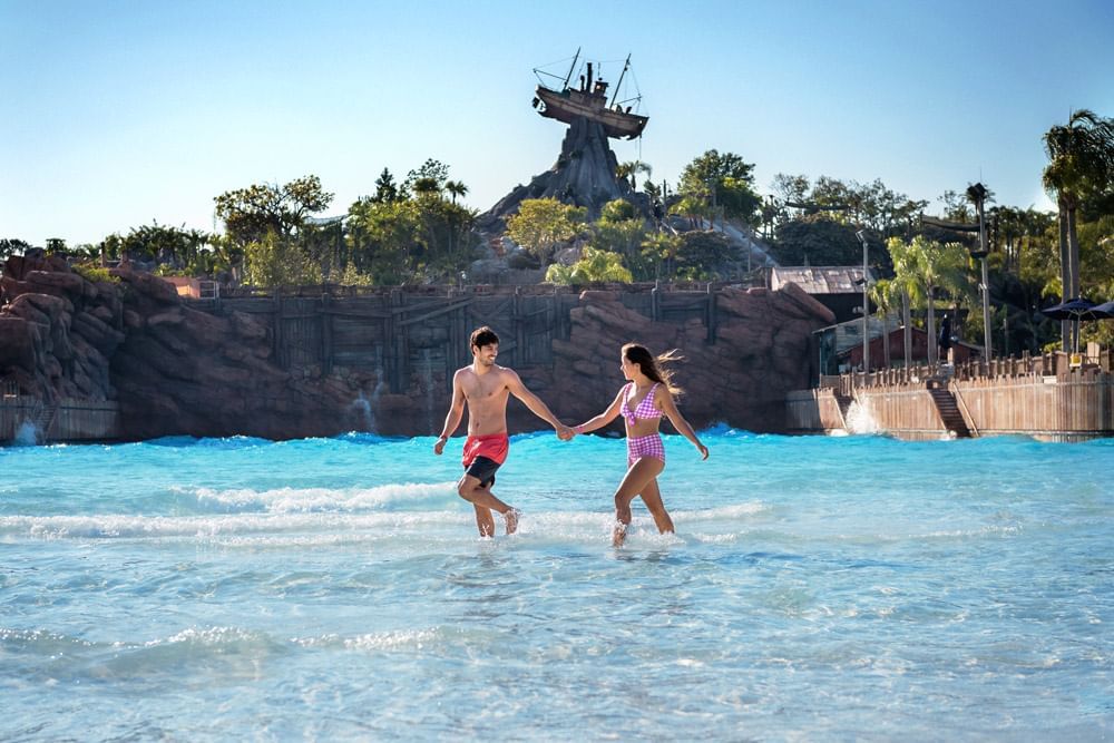 Couple walking through a water park wave pool in Disney’s Typhoon Lagoon near Lake Buena Vista Resort Village & Spa