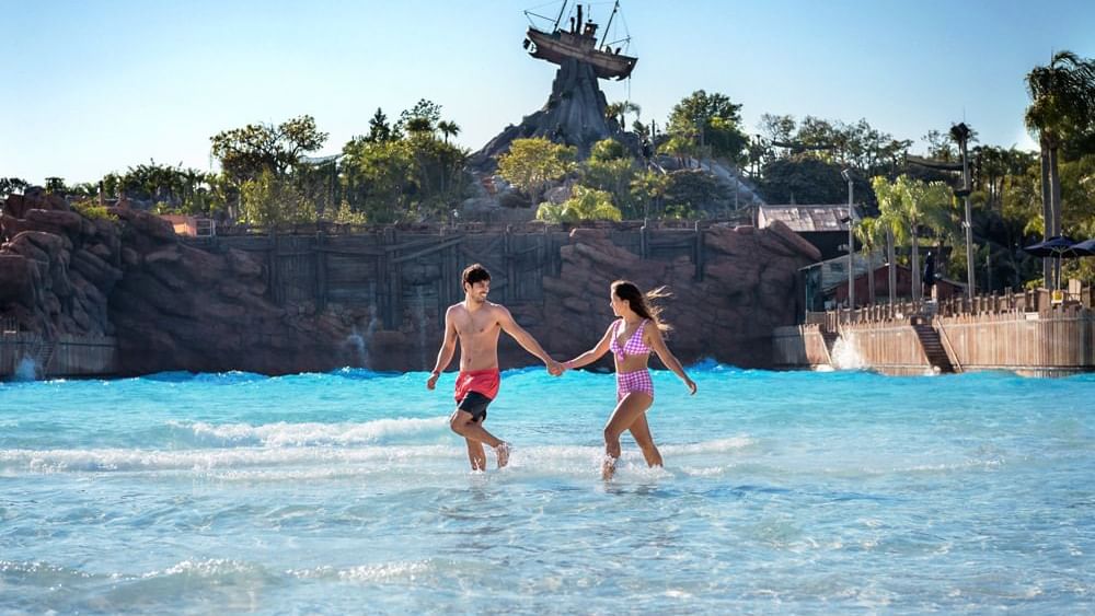 Couple walking through a water park wave pool in Disney’s Typhoon Lagoon near Lake Buena Vista Resort Village & Spa