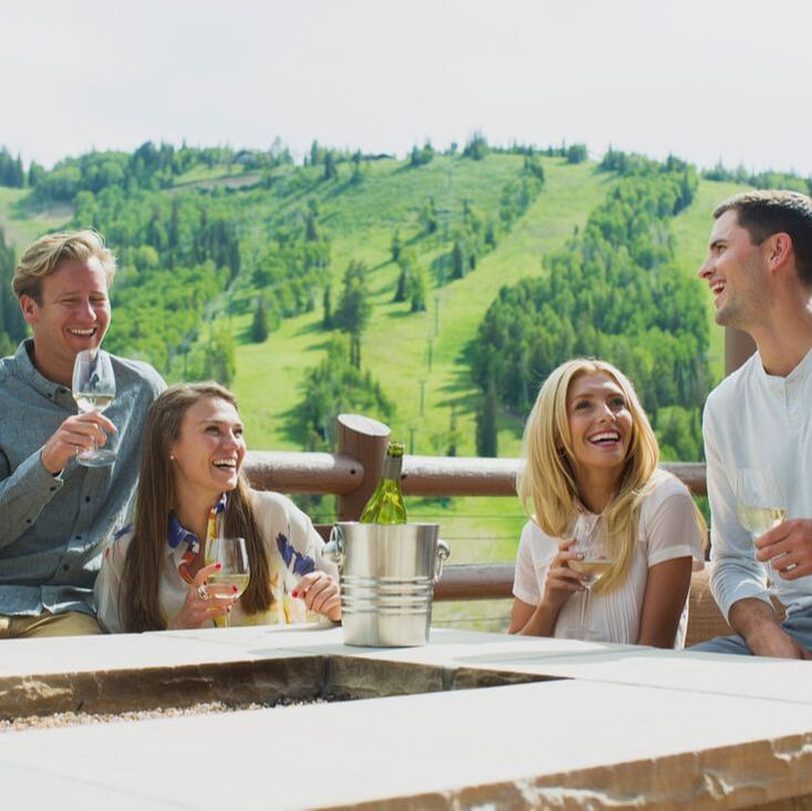 A group of 4, having champagne at a deck in Stein Lodge