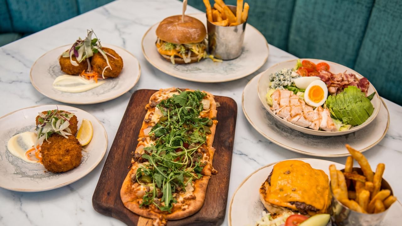 Assorted dishes including flatbread, burgers, salad bowl, and appetizers.