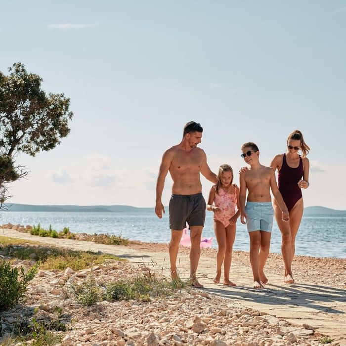 A family walking on the beach near Falkensteiner Hotels