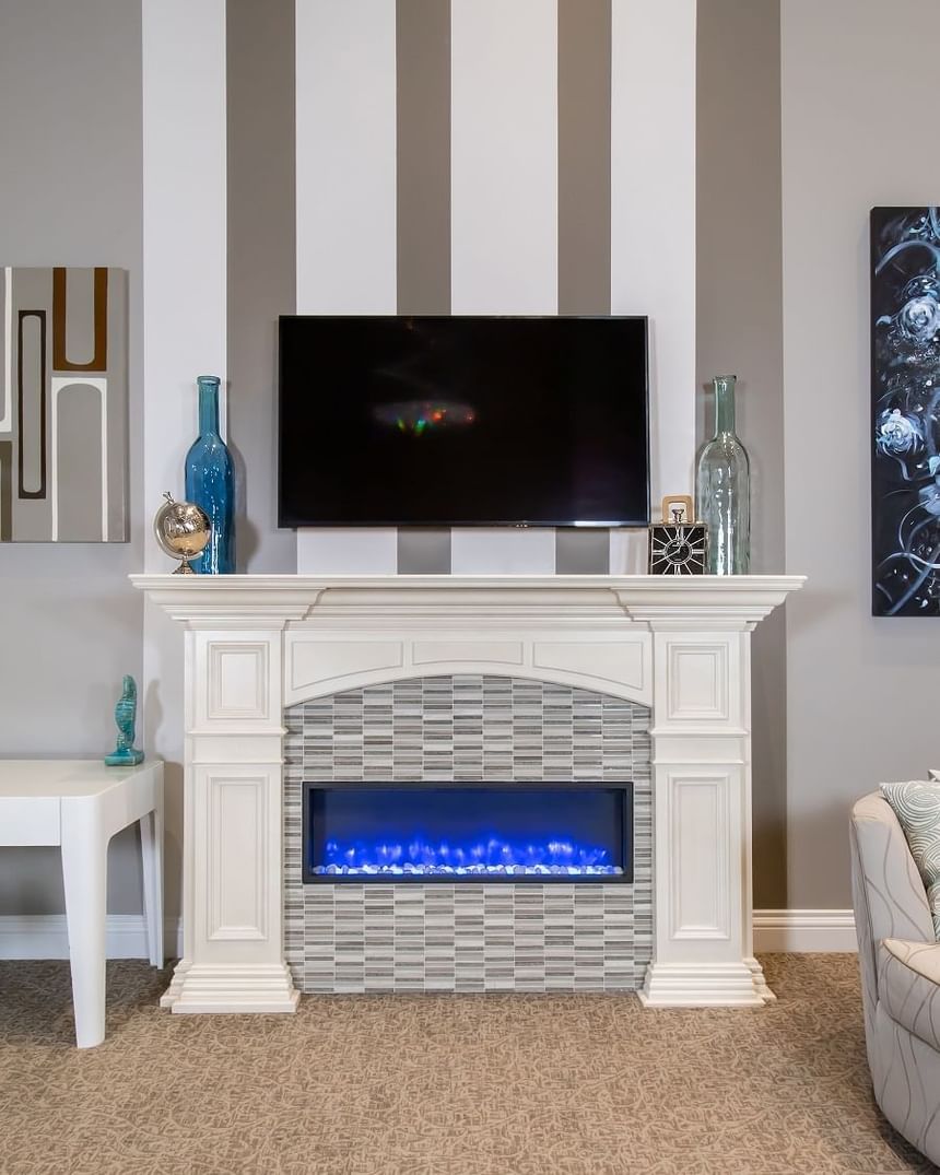 Fireplace, decorative, clock & bottles on the mantelpiece by the TV in Presidential Suite at Retro Suites Hotel
