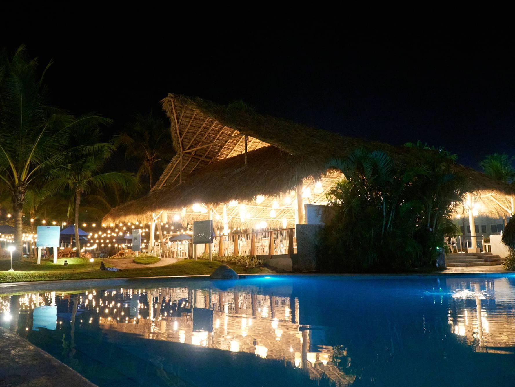 El Pelicano Snack Bar visto desde la piscina enfrente durante la noche.