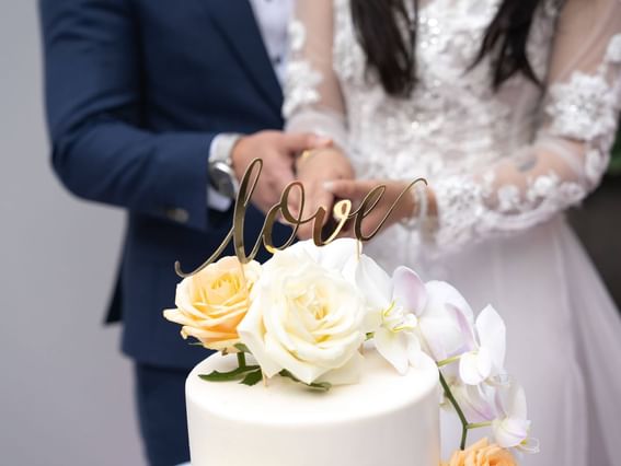 A newlywed couple cuts the decorated wedding cake, celebrating this joyous moment together at Park Hotel Hong Kong
