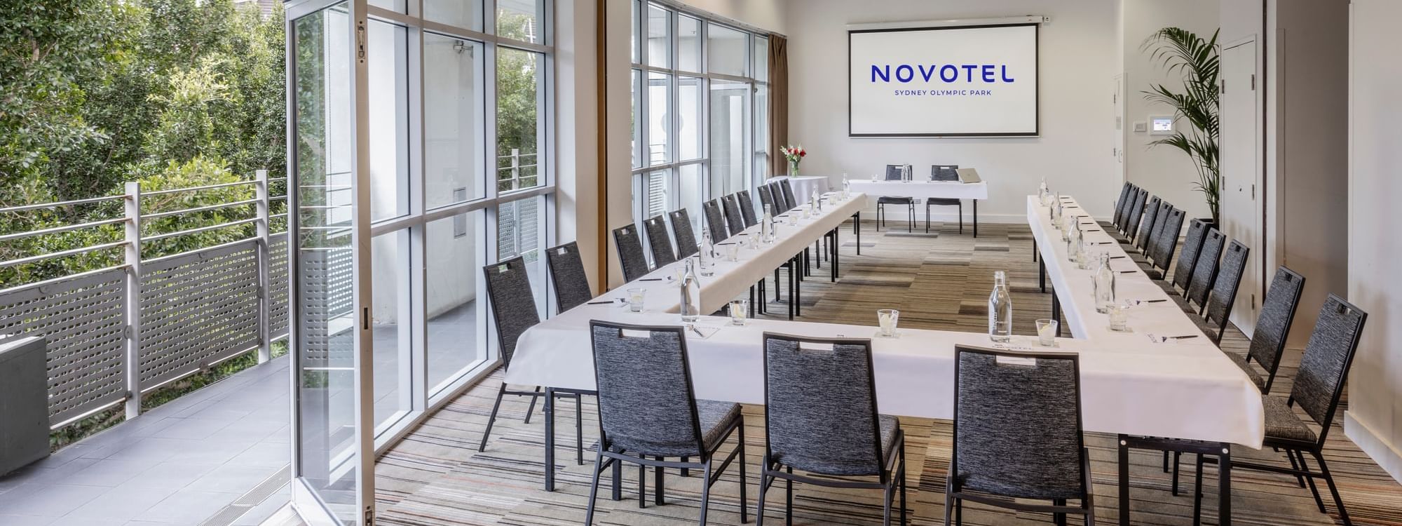 Forest Room featuring a U-shaped table setup, projector screen, and natural light Novotel Sydney Olympic Park