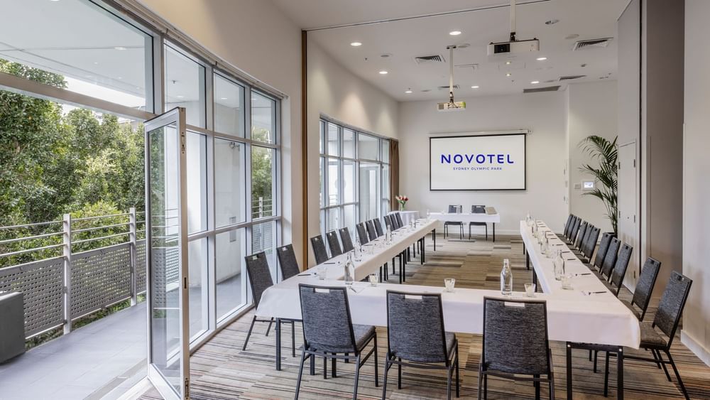 Forest Room featuring a U-shaped table setup, projector screen, and natural light Novotel Sydney Olympic Park