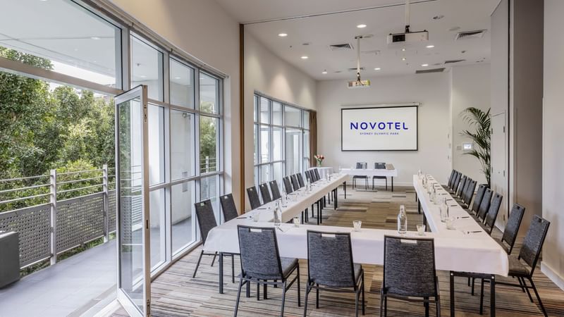 Forest Room featuring a U-shaped table setup, projector screen, and natural light Novotel Sydney Olympic Park