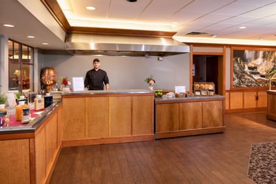 A cheerful chef stands ready at the omelet station in the bright and wood-trimmed dining area of Lake Placid Club Grandview