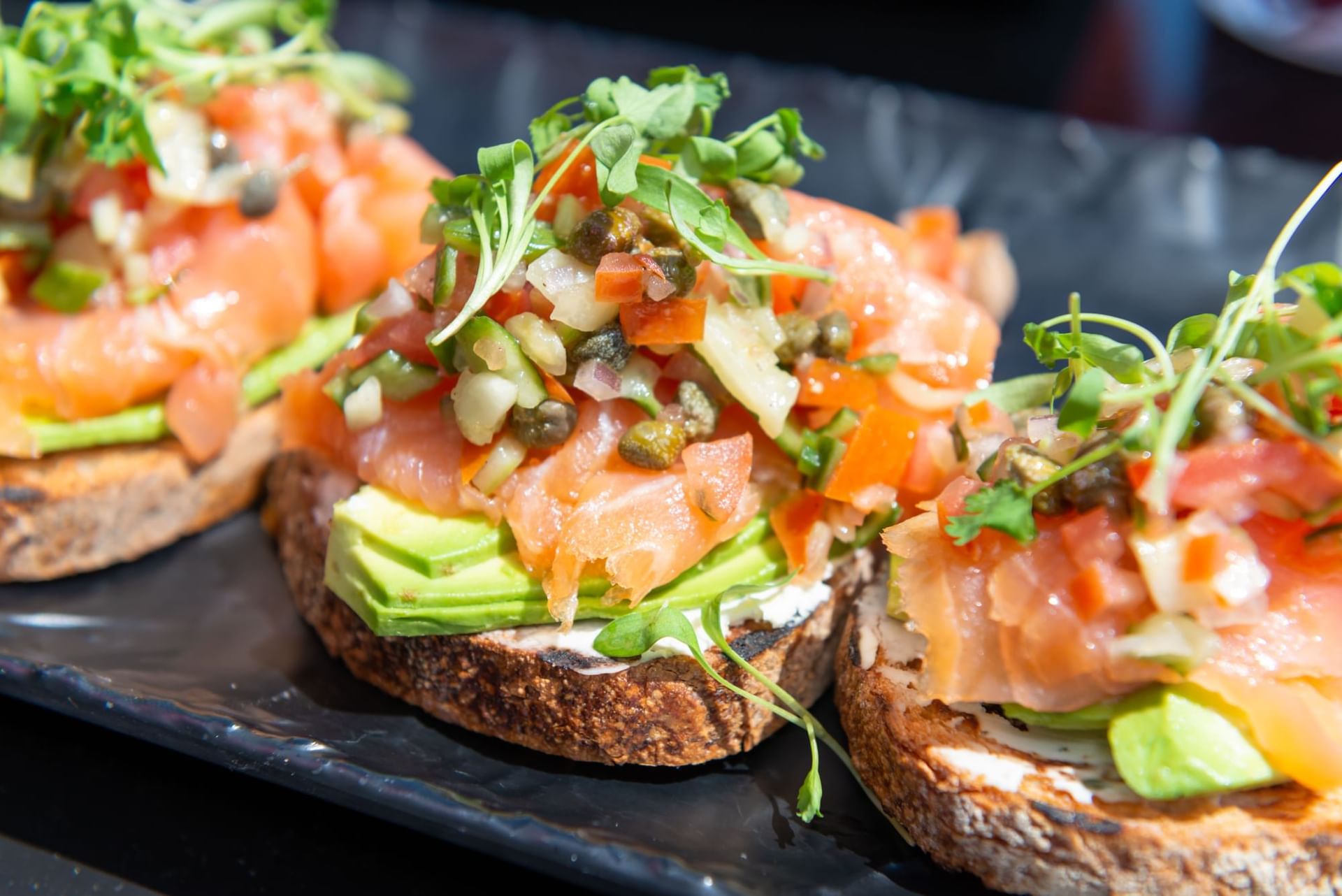 Close-up of three Smoked Salmon Avocado Toast on a tray at The Godfrey Chicago