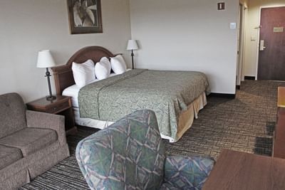 A comfortable king guest room at Hotel Topeka at City Center with sofa bed and work desk.