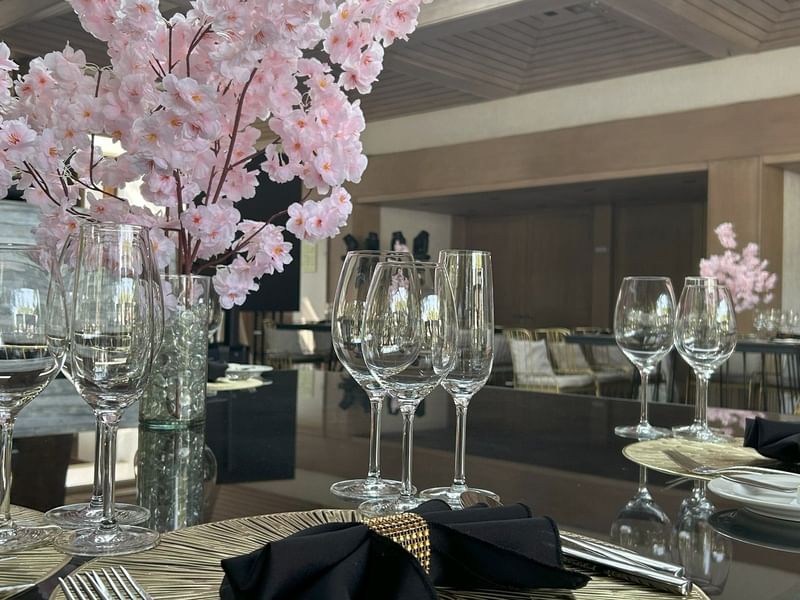 Elegantly set dining table with black napkins and cherry blossom centerpieces in the Salón y Foyer Kioto at Grand Fiesta Americana Sumiya Cuernavaca.