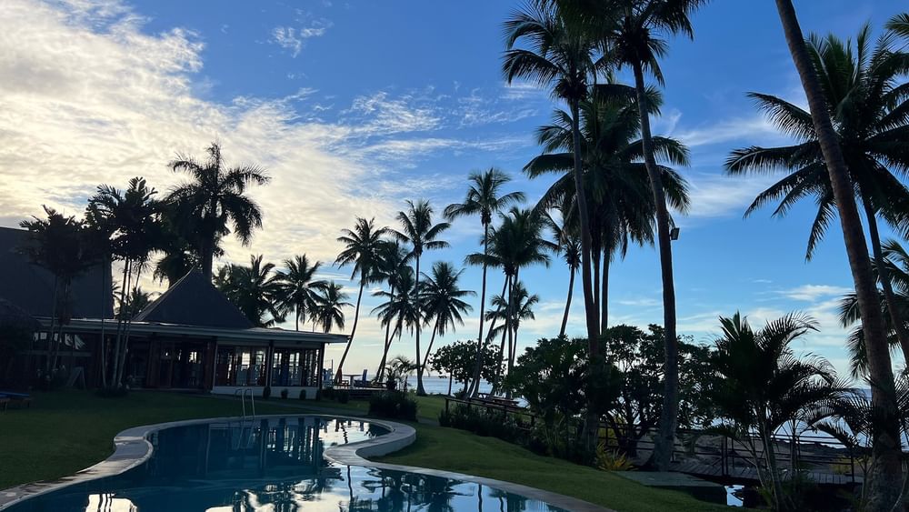 Resort pool with ocean view and palm trees at Tambua Sands Beach Resort in Sigatoka.