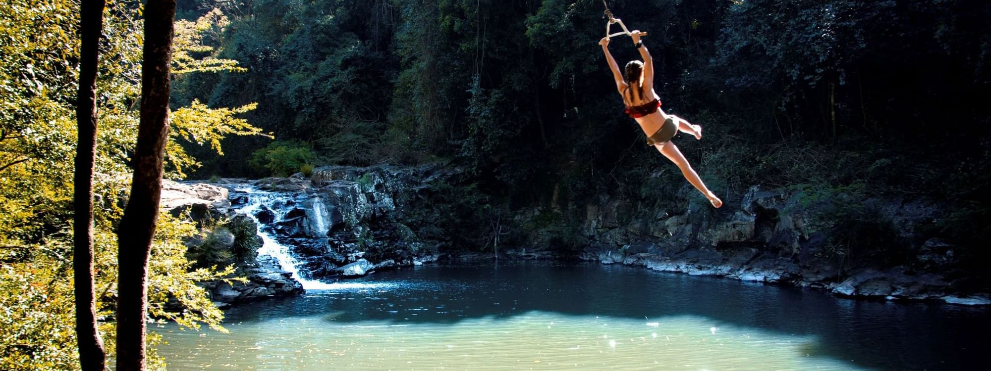 Lady swinging off a rope by the lagoon near Novotel Sunshine Coast Resort