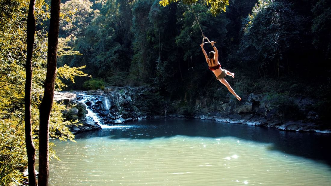 Lady swinging off a rope by the lagoon near Novotel Sunshine Coast Resort