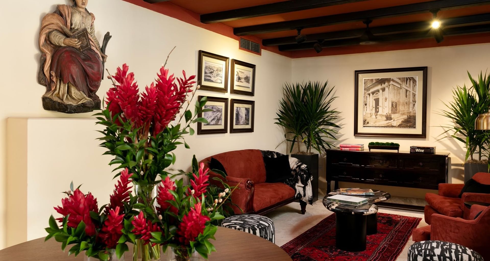 Elegant living room in Veranda Terrace with red furniture, a wooden table, framed artwork, and potted plants.