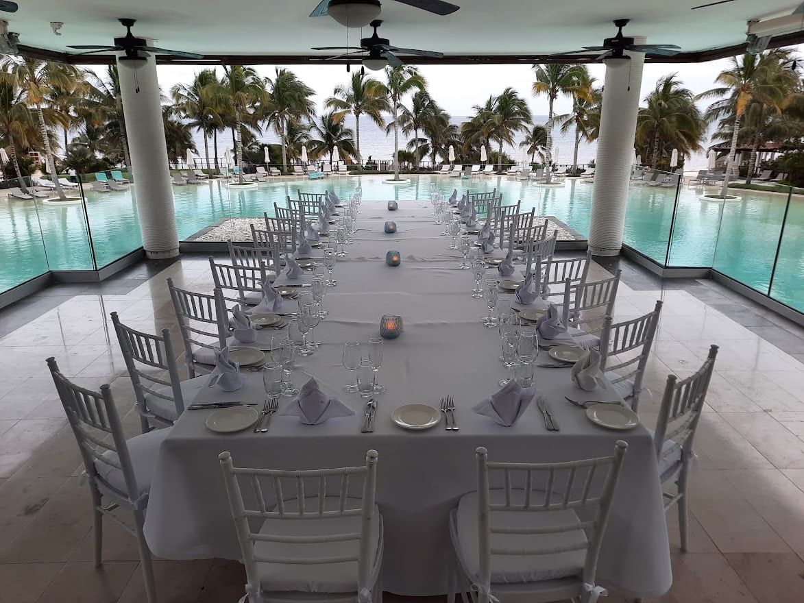 Group dining set-up with pool & ocean view with palm trees in the Vistas at Haven Riviera Cancun