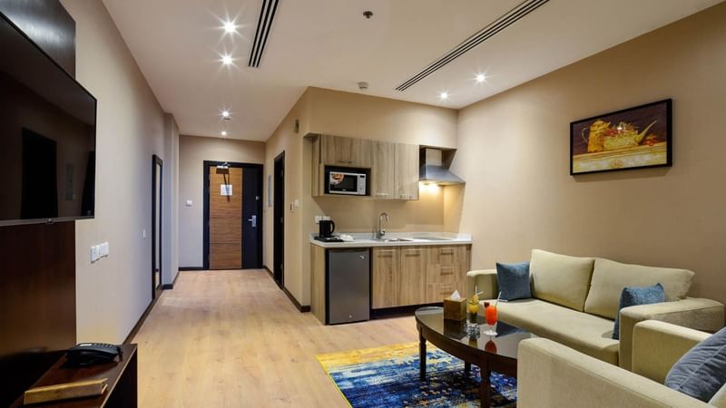 Living area with sofa and a kitchenette in Junior Suite at Naviti By Warwick Dammam