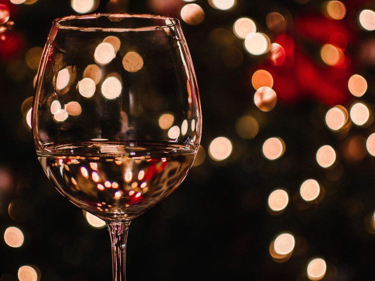 Close-up of a glass of wine by Christmas tree in the background at Hotel Grand Chancellor