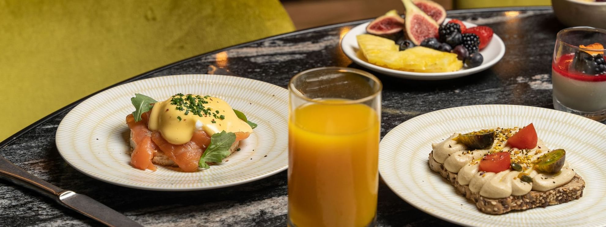 Close-up of breakfast toast, juice, oats & fruits served on a table at Azimuth Barcelona