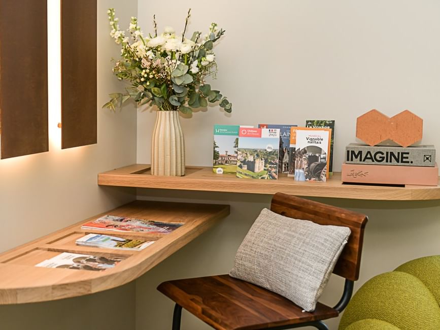 Bureau en bois avec livres, magazines et vase de fleurs à l'Hôtel Rivella.