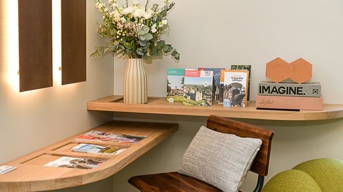 Bureau en bois avec livres, magazines et vase de fleurs à l'Hôtel Rivella.