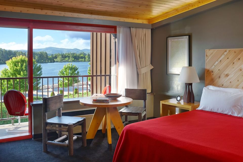 Lake House Balcony King with bed by a wooden dining set under a timber ceiling overlooking the lake at High Peaks Resort