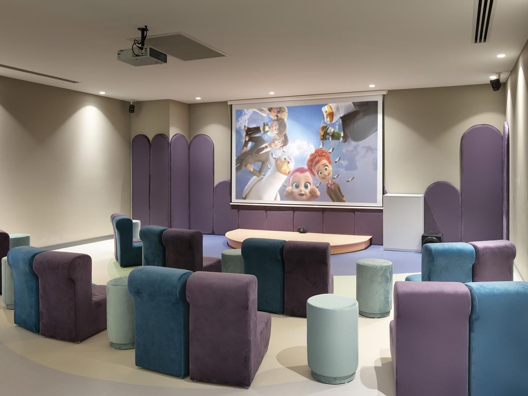 Movie room with chairs and animated movie playing on the projector screen in Tini Kids Club at Titanic Deluxe Golf Belek